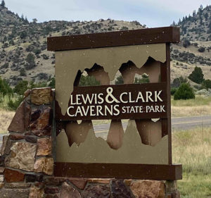 Entrance sign for the Lewis and Clark Caverns State Park. Rock structure supporting a square metal sign that features cut outs resembling the inside of a cave.